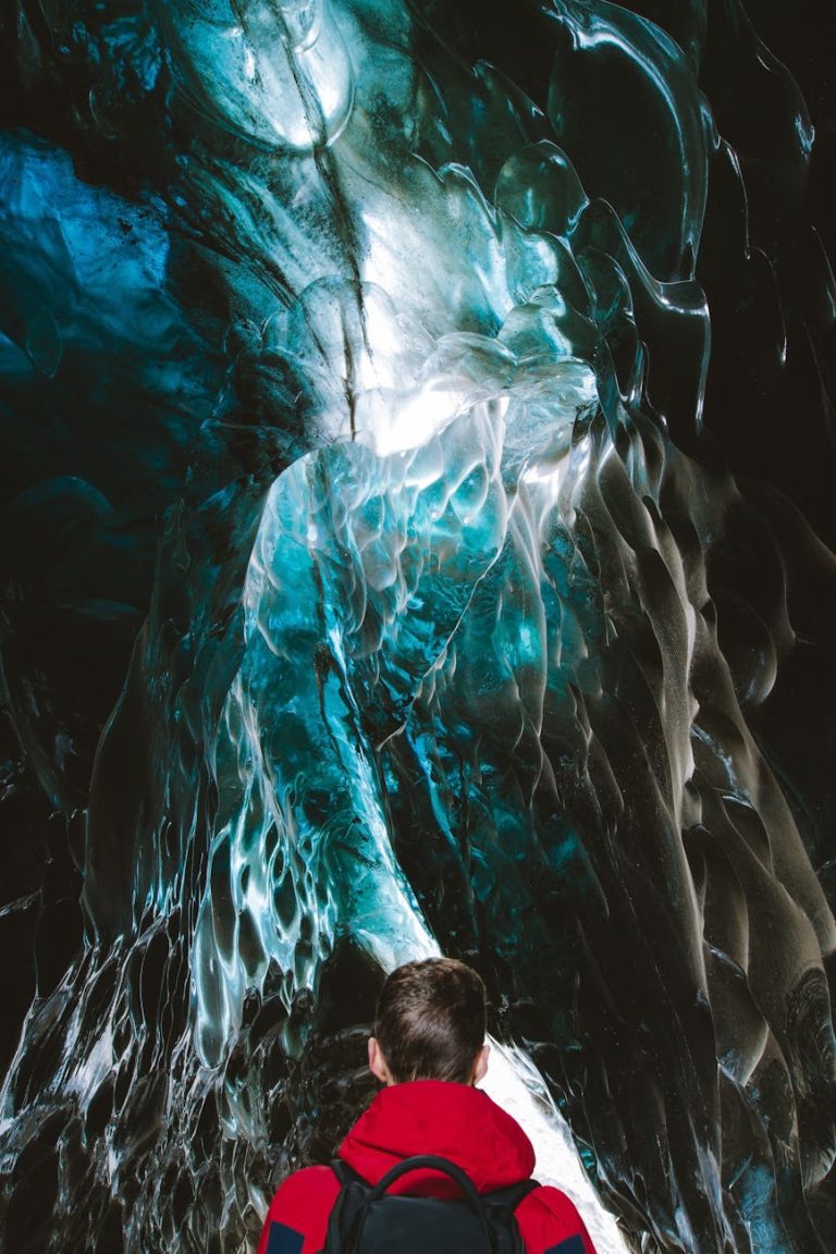 Person exploring a stunning turquoise ice cave in Iceland, showcasing frozen beauty.