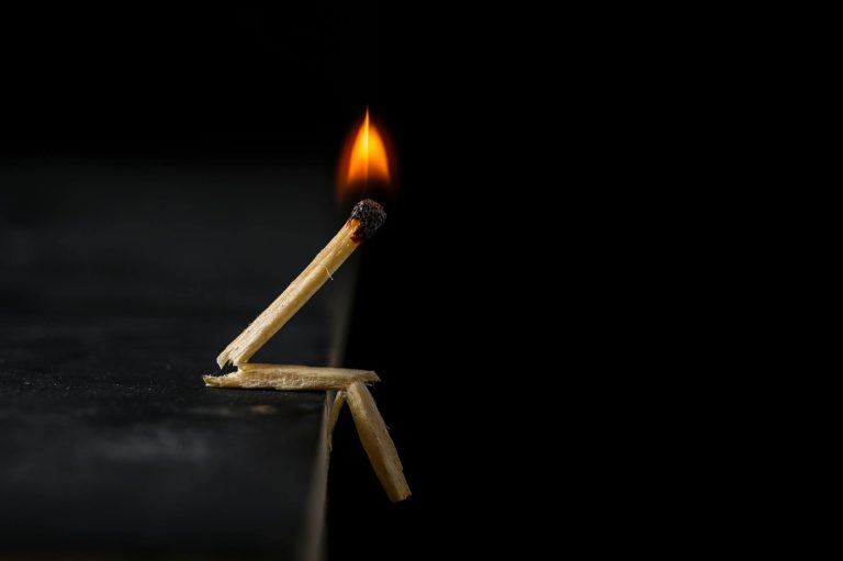 Artistic matchstick figure with a burning flame against a dark background, showing creativity.