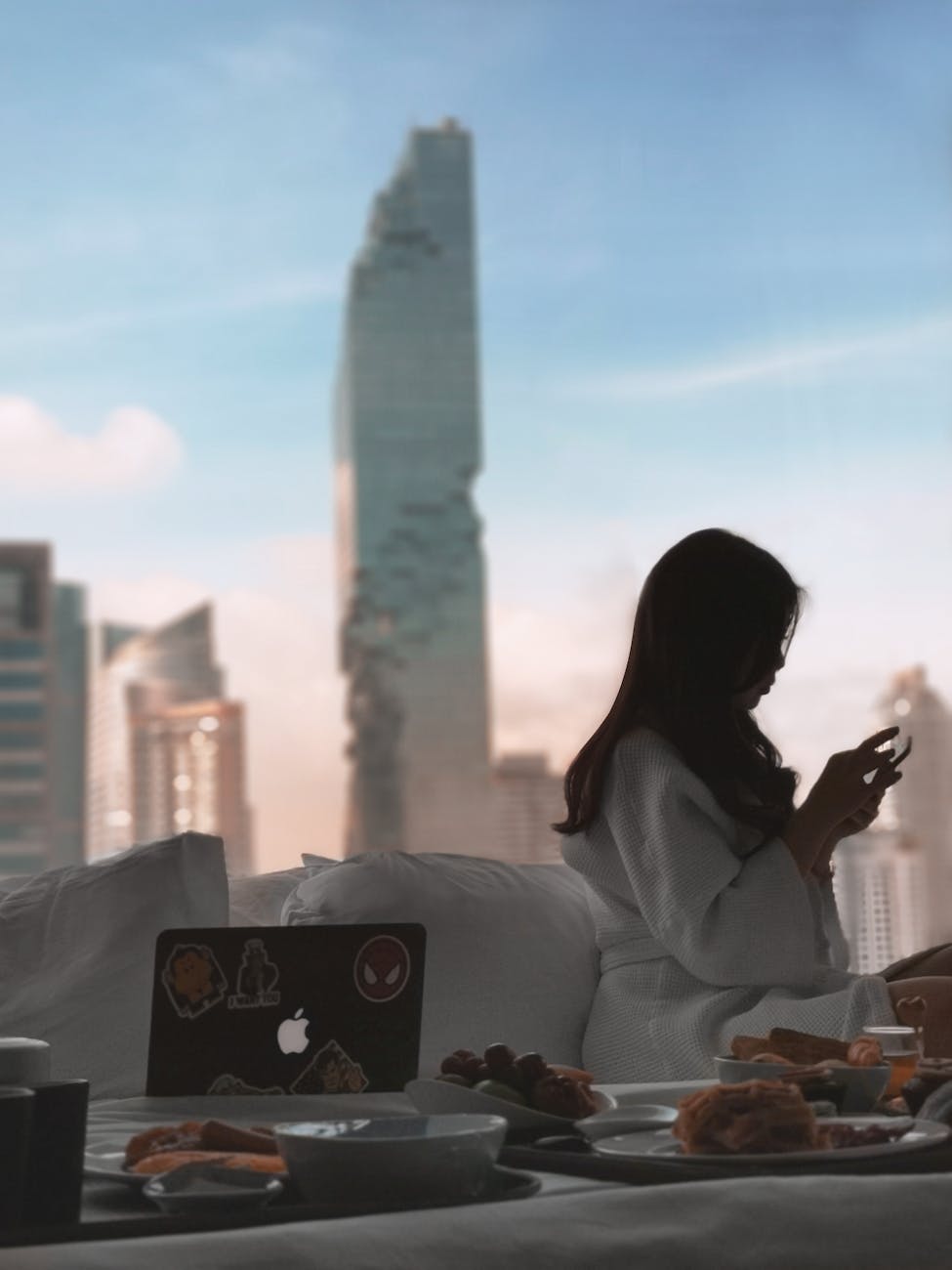 A serene morning scene of a woman relaxing with breakfast in a luxurious Bangkok hotel room.