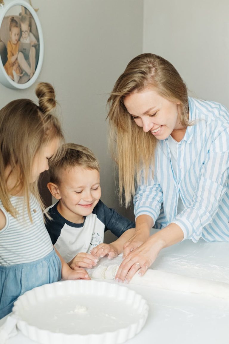 A smiling mother and her two children enjoy quality time making dough together indoors.