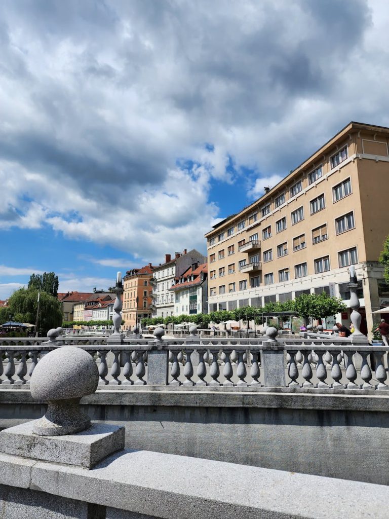 Picturesque view of Ljubljana's riverside architecture on a sunny day with vibrant clouds.
