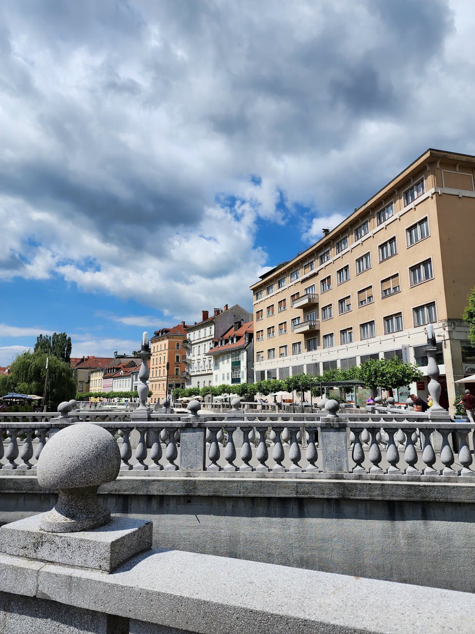 Picturesque view of Ljubljana's riverside architecture on a sunny day with vibrant clouds.