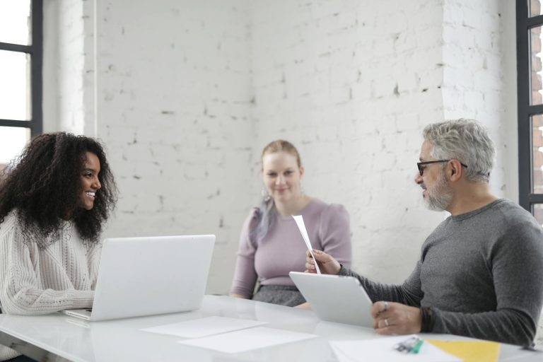 Business professionals engaging in a collaborative meeting with laptops and documents in a modern office setting.