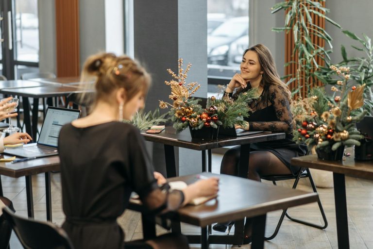 Women engaged in discussion in a festive office setting with Christmas decor.