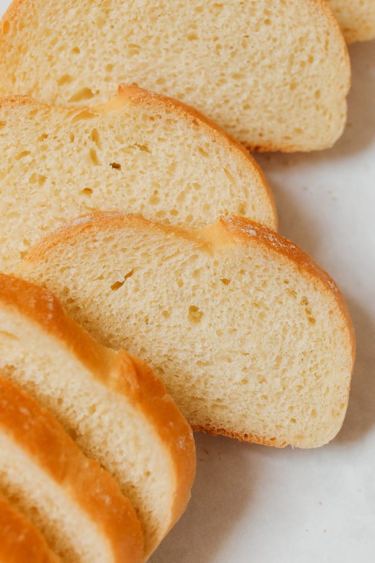 A close-up view of freshly sliced homemade bread loaf on a white background.