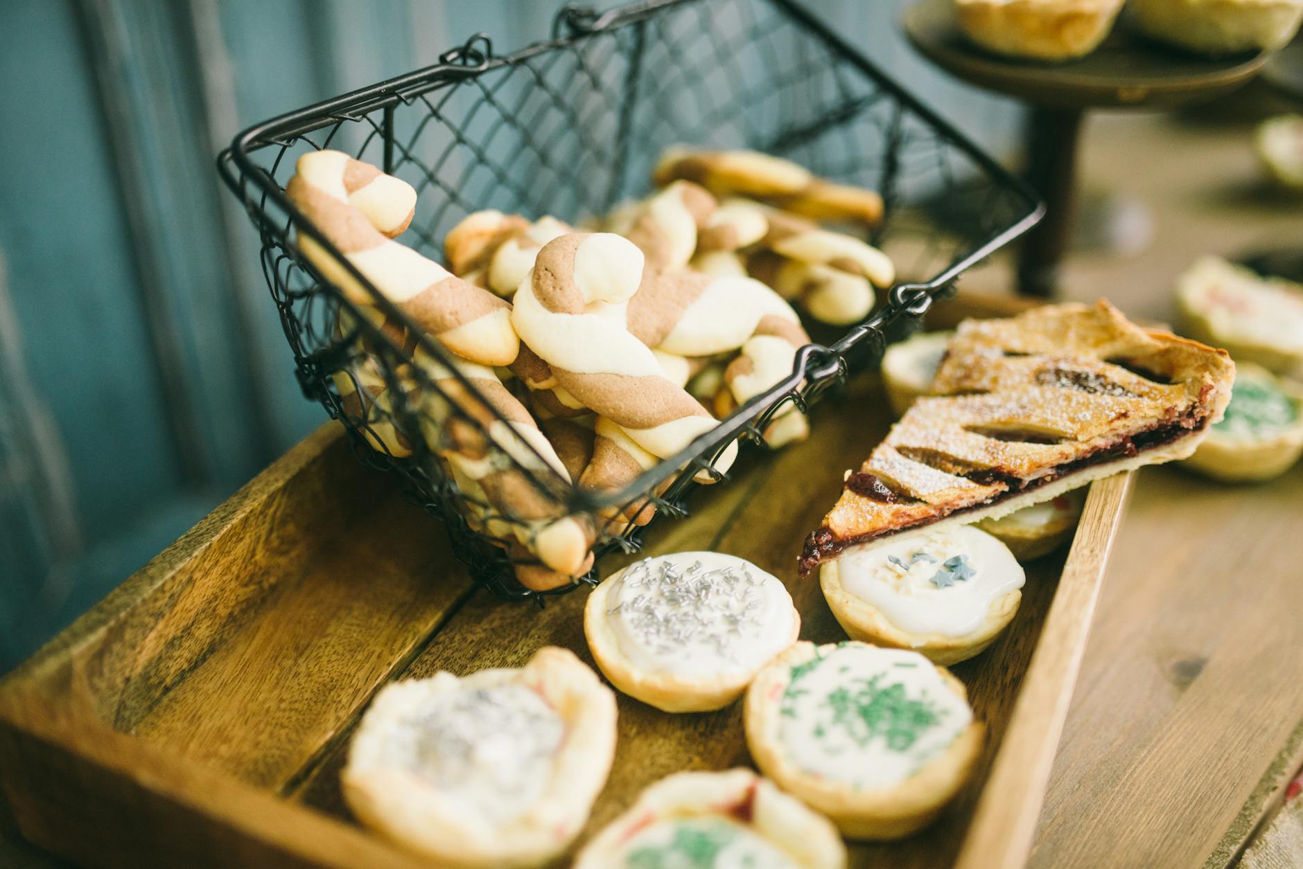Delicious assortment of cookies and pies in a rustic metal basket and wooden tray.