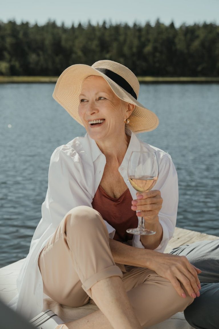 Senior woman enjoying a summer day on a pier with a glass of wine.