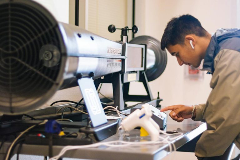 Young student interacts with jetstream apparatus in an engineering lab.