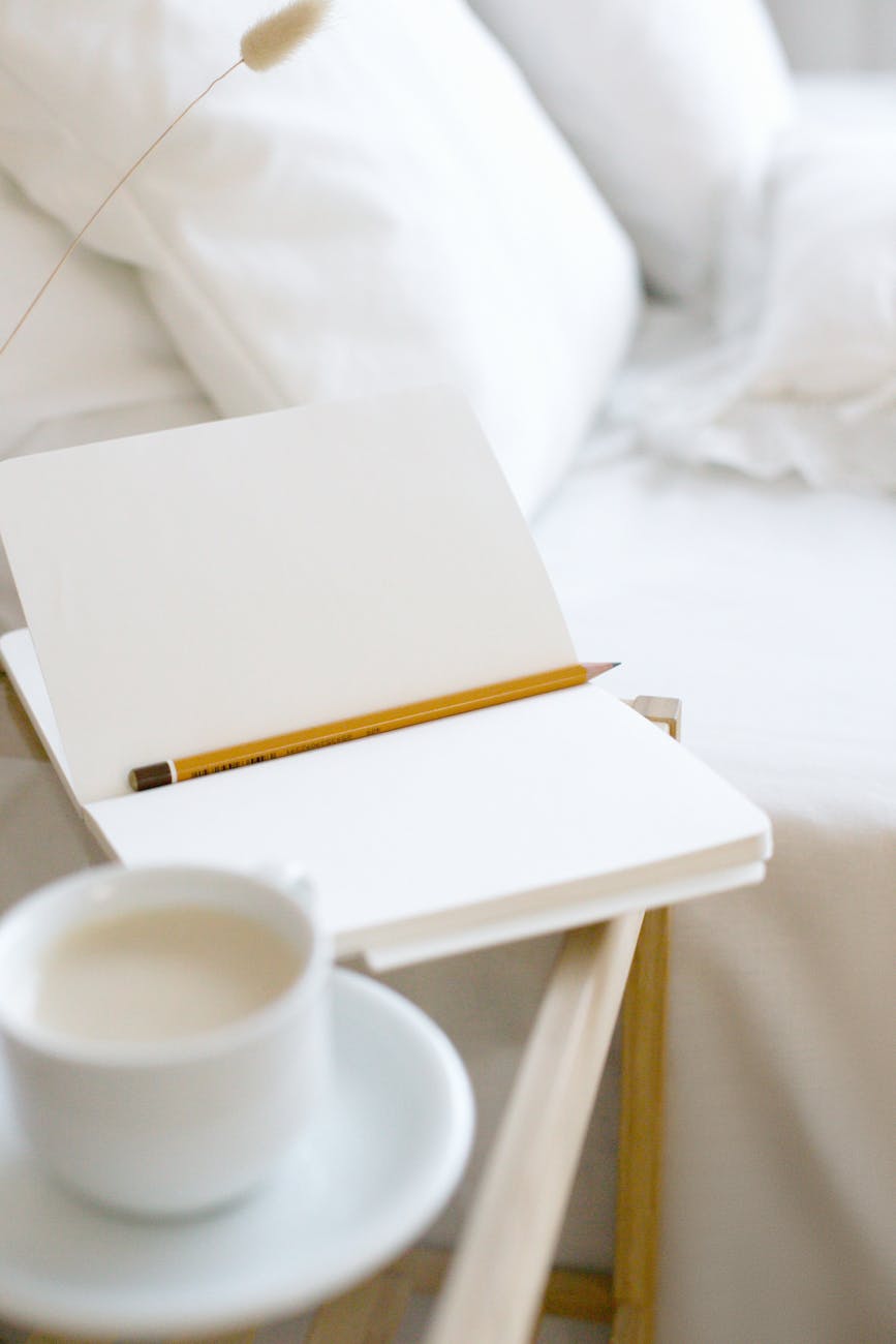 A minimalist home workspace featuring an open notebook and pencil with coffee on a wooden tray.