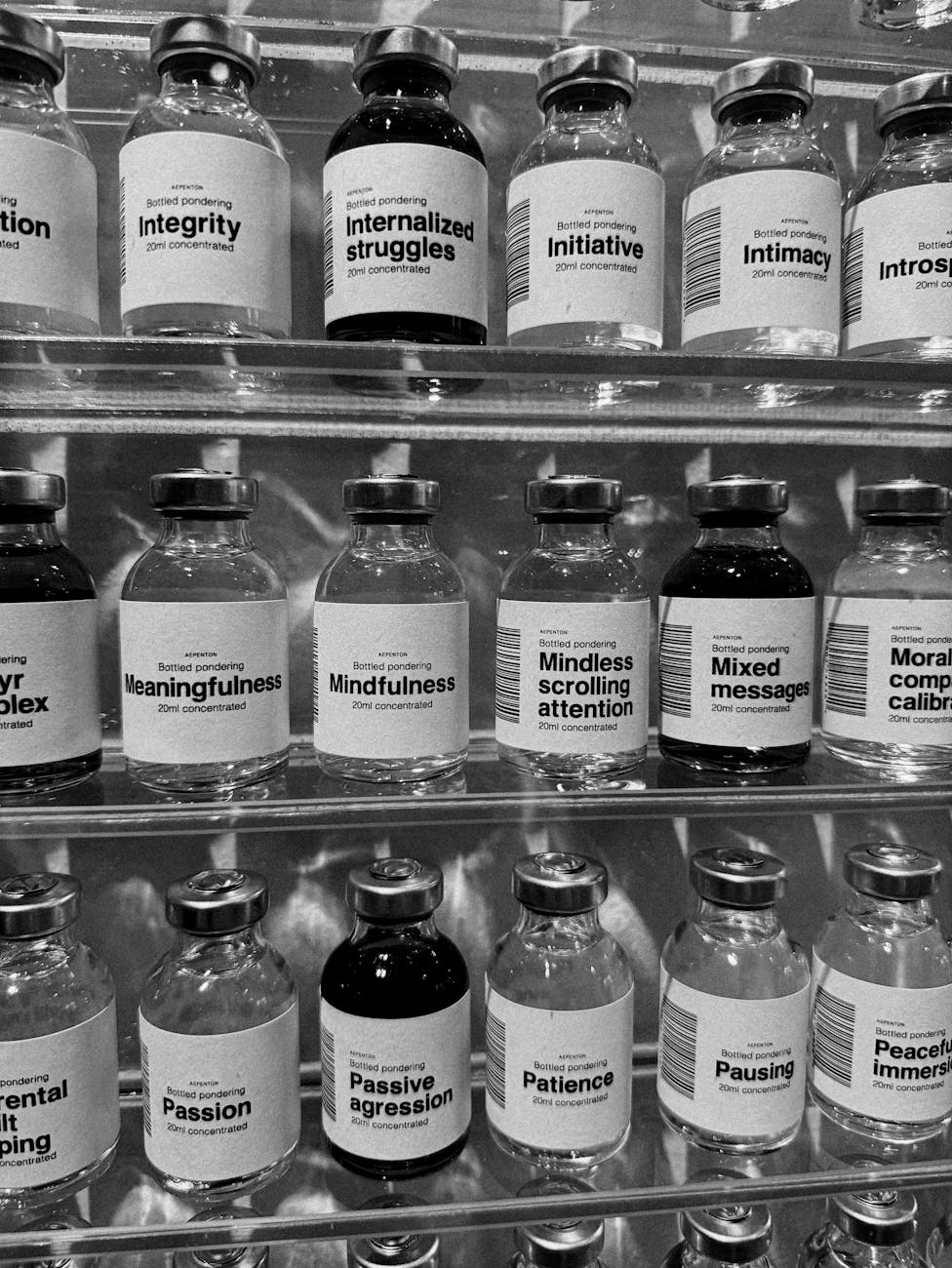 Black and white photo of bottles labeled with concepts like integrity and mindfulness, Denmark.