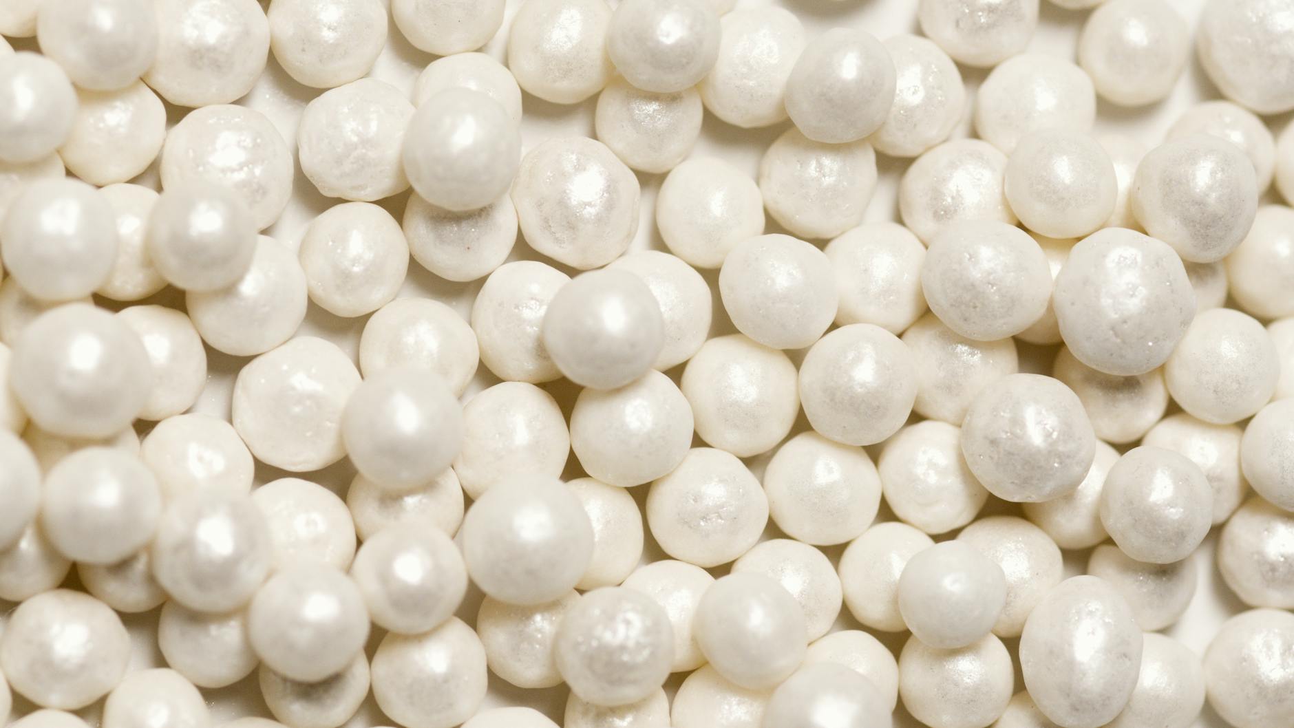 Detailed image of shiny white pearls, highlighting the texture and smooth surface for decorative use.