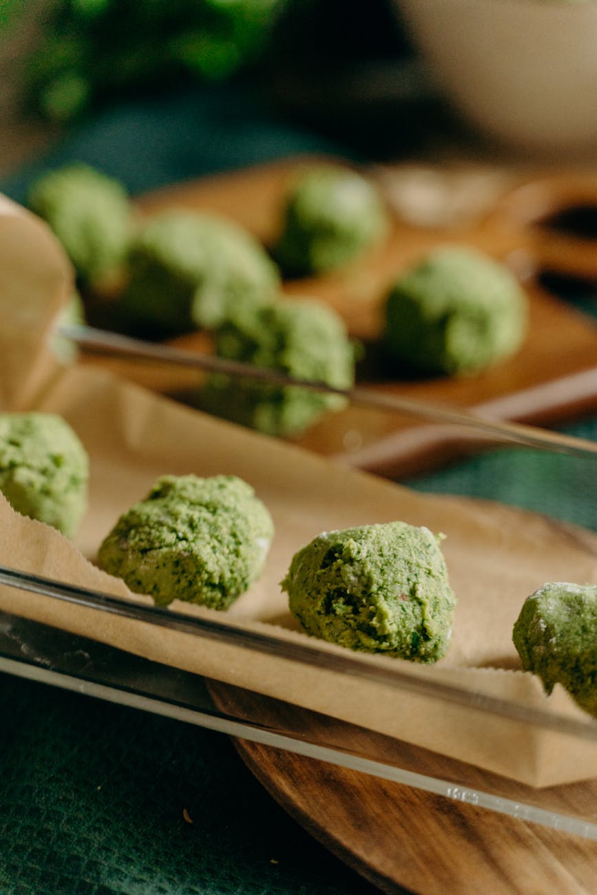 Close-up of freshly prepared green vegetal balls on parchment, perfect for a vegetarian meal.