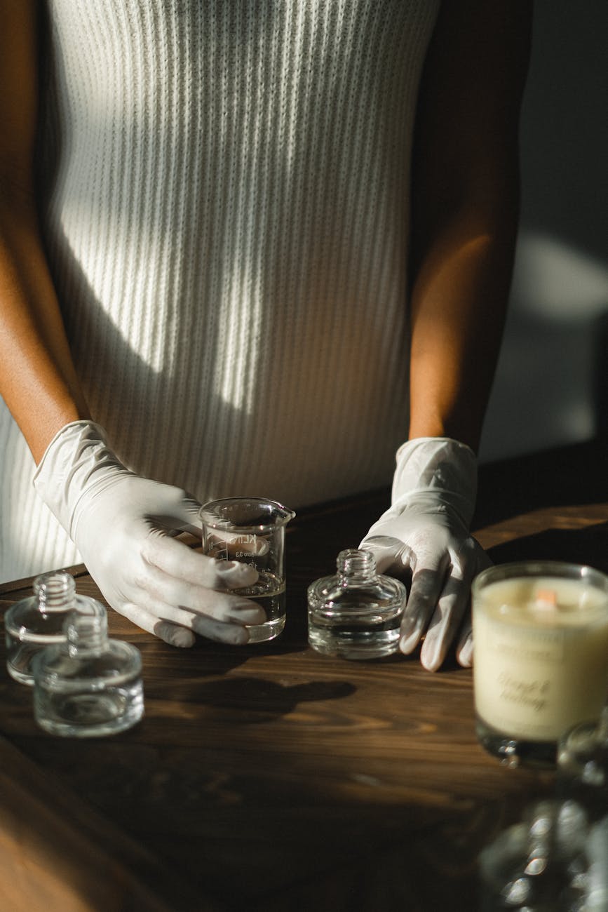 Aromatic essence preparation with gloved hands and glass jars indoors.