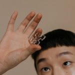 Person holding a transparent puzzle piece, focusing on the hand and expression.