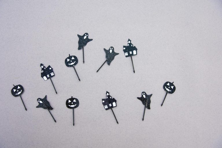 Black ghost and pumpkin cutouts scattered on a light surface perfect for a Halloween party.