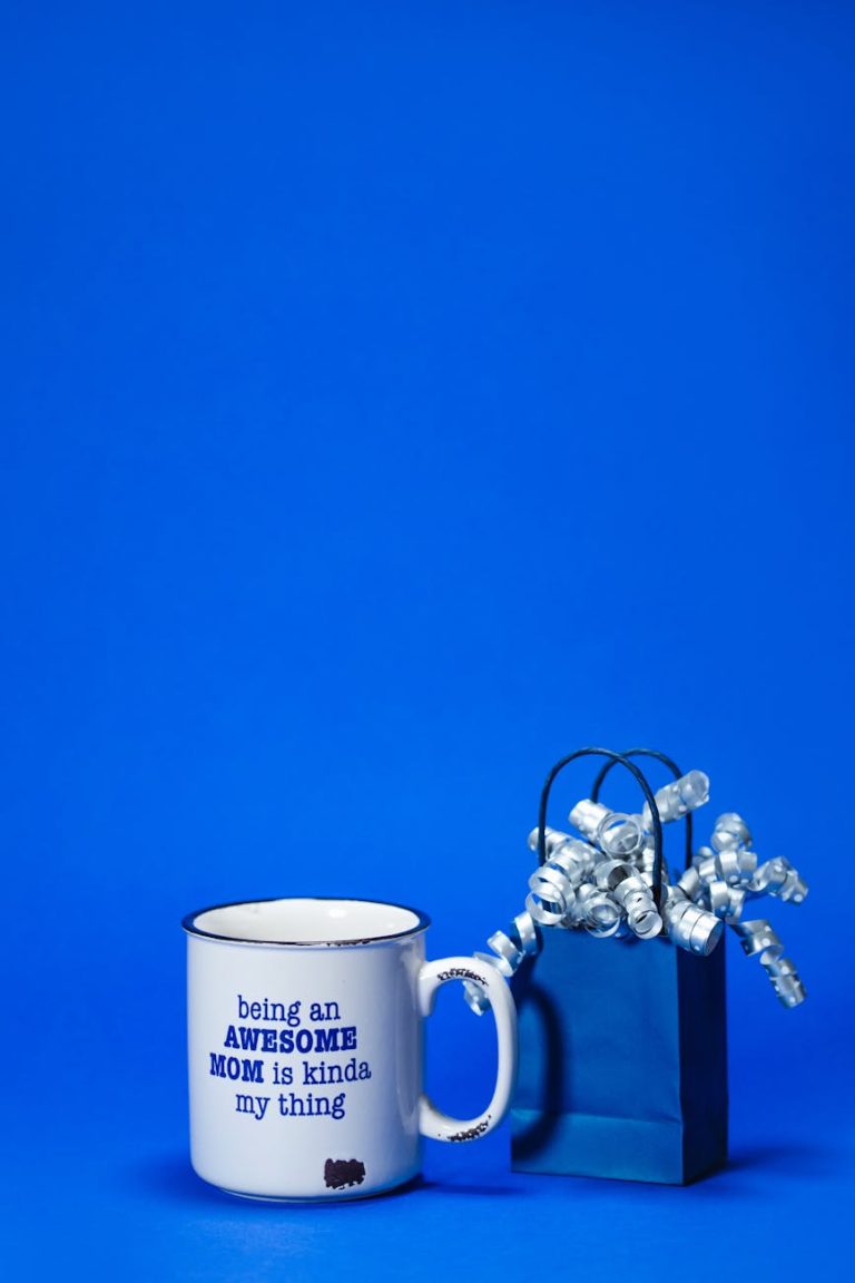 A ceramic mug and gift bag on a vibrant blue background, ideal for Mother's Day gifts.
