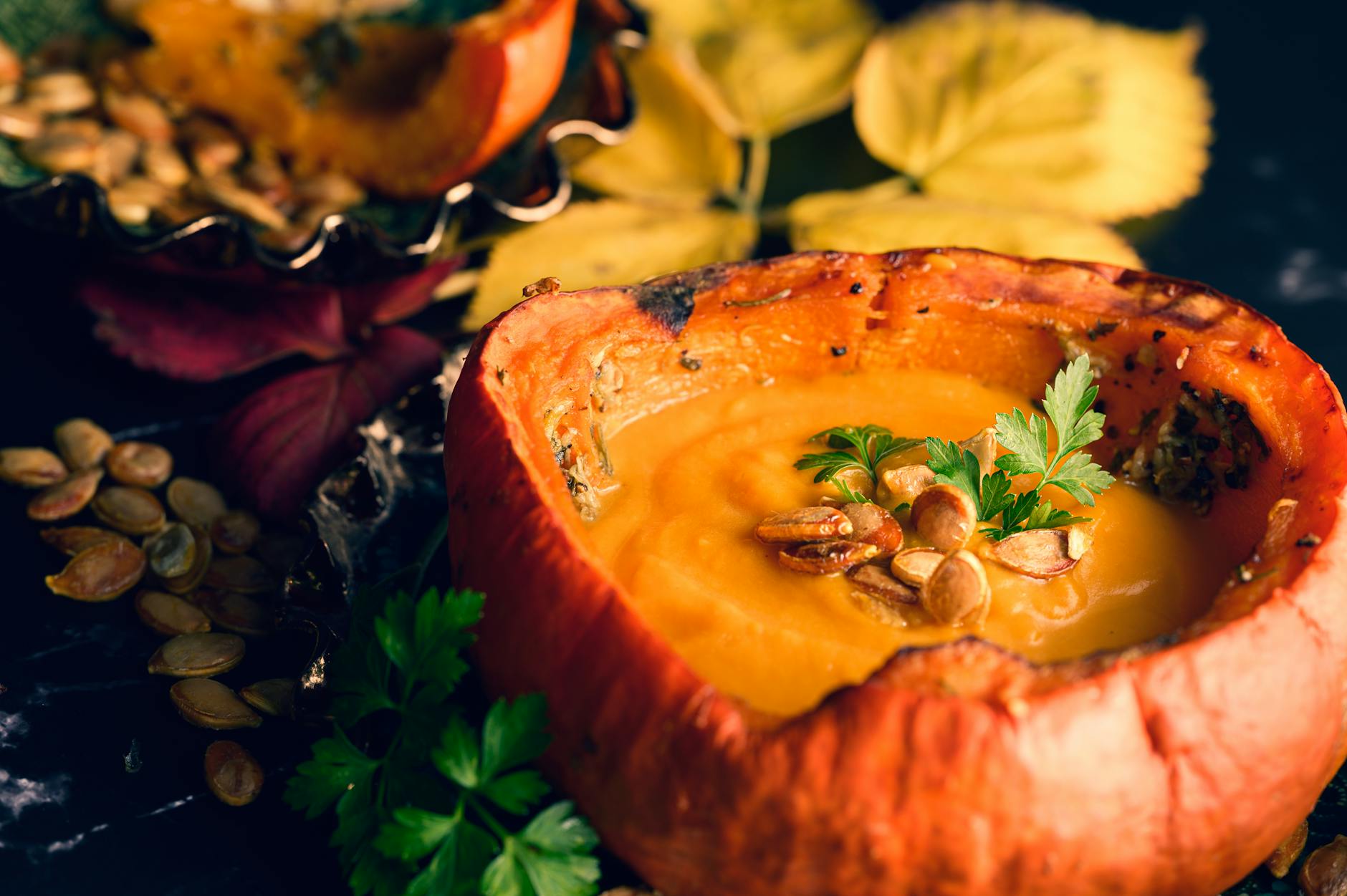 Delicious creamy pumpkin soup served in a pumpkin bowl. Perfect for a hearty autumn dinner.