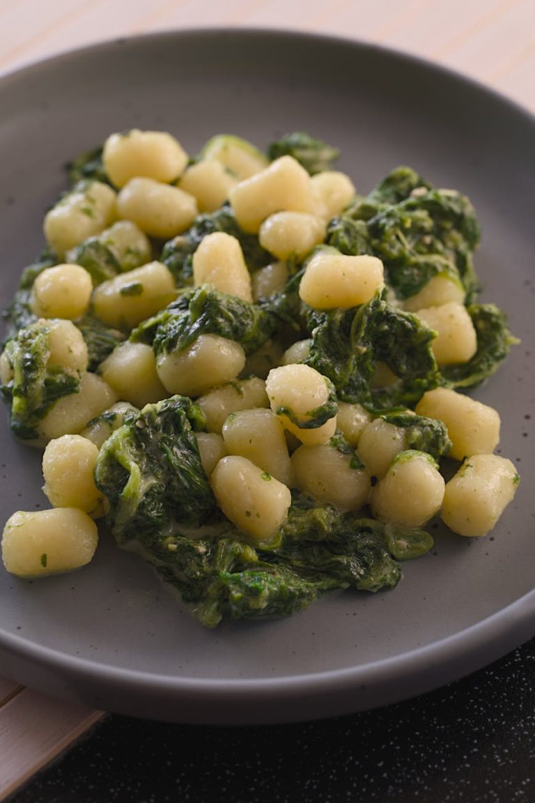 Delicious creamy spinach gnocchi served on a black plate. Perfect comfort food.