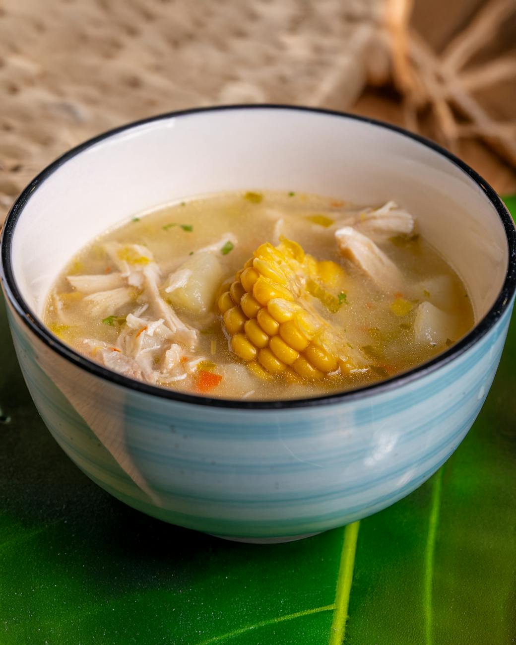 Warm chicken corn soup served in a blue bowl, perfect for a cozy meal.