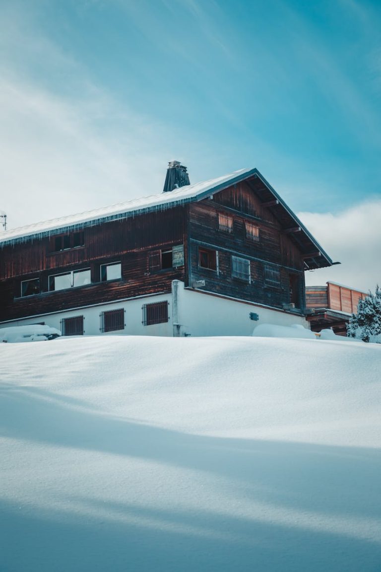 Wooden chalet blanketed in snow amidst wintery Megève landscape in France.