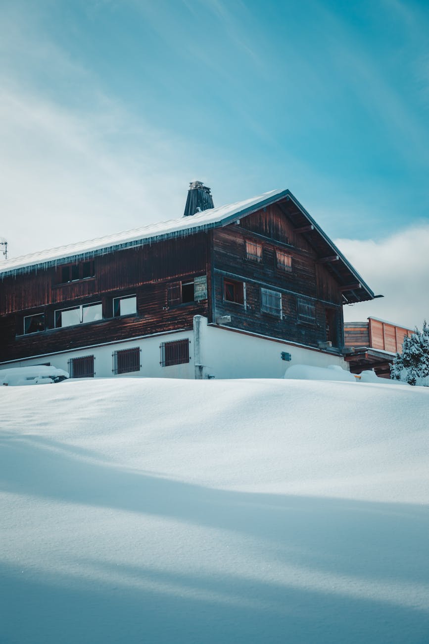 Wooden chalet blanketed in snow amidst wintery Megève landscape in France.