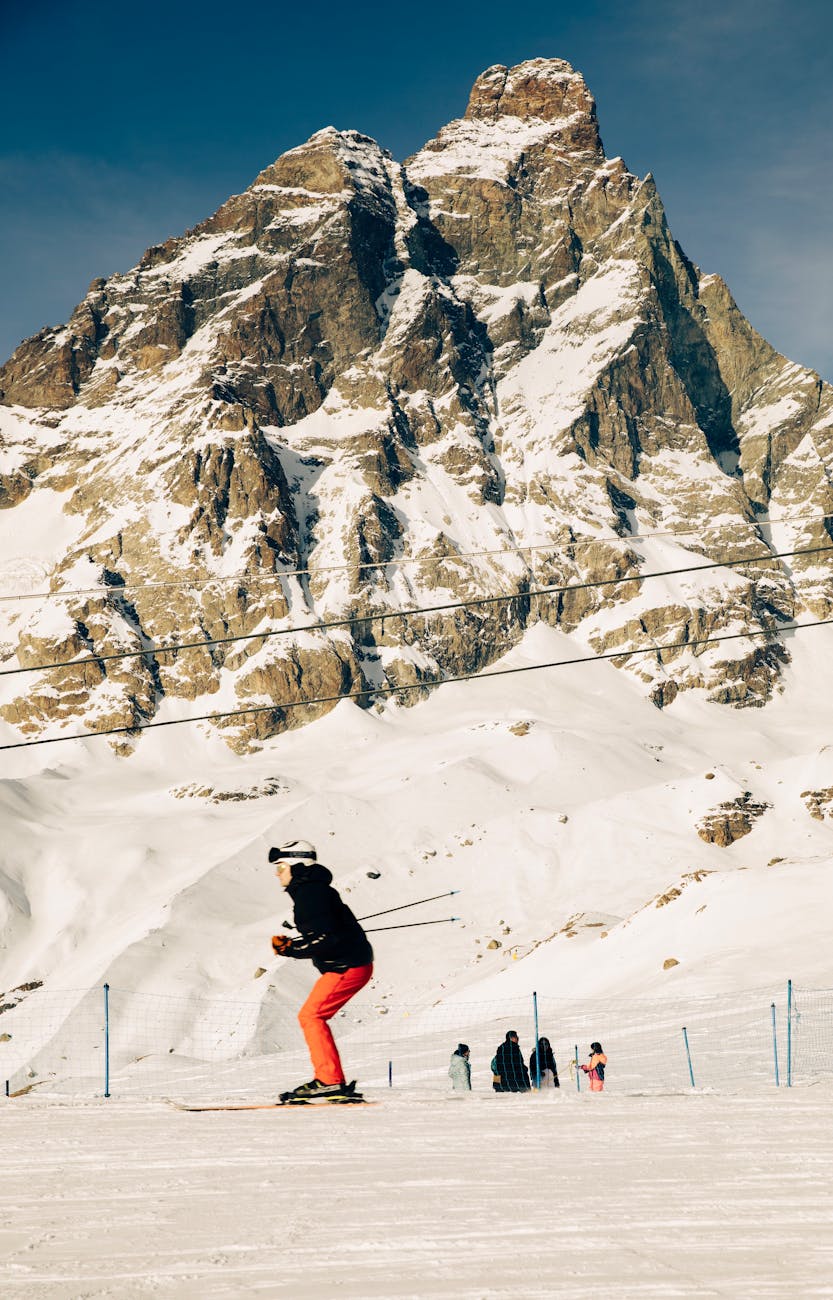 A skier descends a snowy slope in a stunning alpine mountain setting, perfect for winter sports.