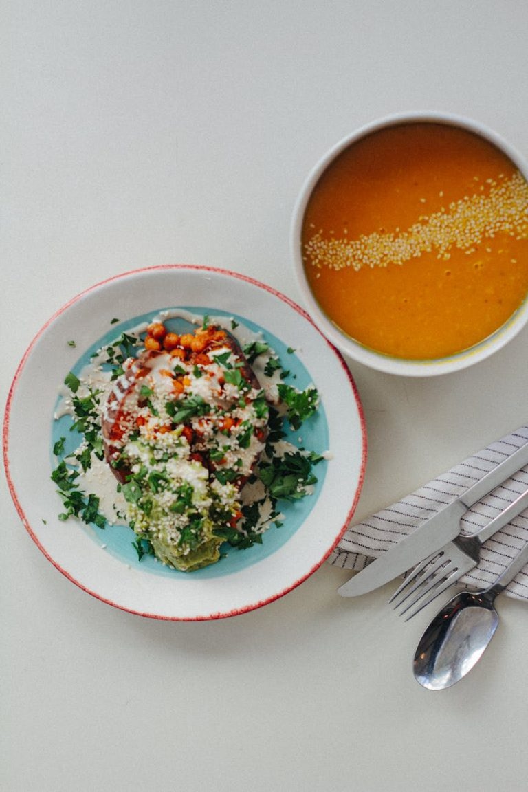 Flat lay of a colorful vegetarian meal with quinoa and pumpkin soup on a table.
