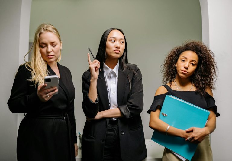 Three diverse businesswomen in professional attire in an office setting.