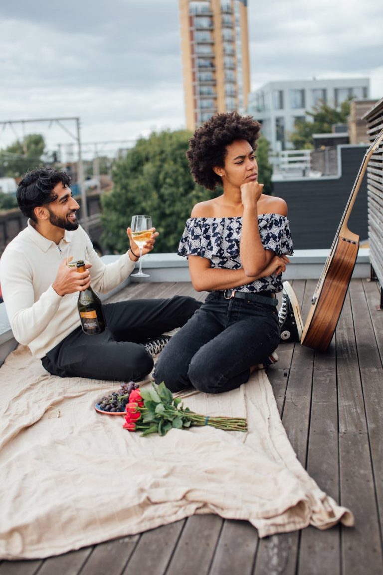 Couple enjoying a rooftop picnic with wine and roses, capturing a romantic moment.