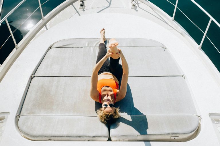 Woman exercising on yacht, enjoying sunny day with yoga routine outdoors.