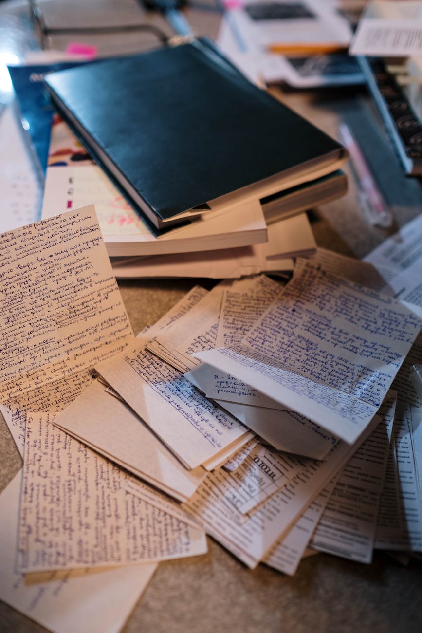 Scattered handwritten notes and books on a desk, perfect for study or research themes.